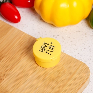 Close-up of yellow round plastic sauce container with HAVE FUN text on bamboo board