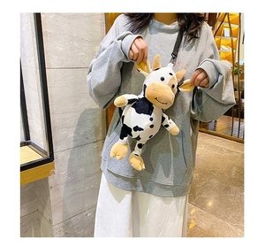 Lifestyle view of a cute plush cow crossbody bag with black and white spots and horns