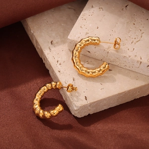 Gold-plated C-shaped hoop earrings with spiral texture on elegant silk background