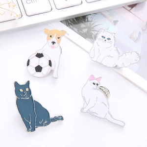 Set of four unique enamel pins featuring white dogs and diverse cat breeds on a desk