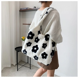 Close-up of fluffy plush shoulder bag with black floral patterns and soft texture