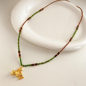 Detail of beaded necklace with tiger eye beads and a golden elephant charm pendant