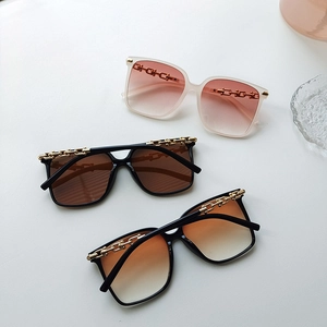 Close-up of oversized square sunglasses with gradient lenses and gold chain link temples