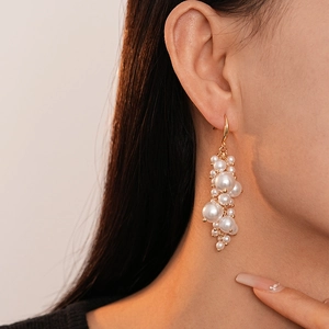 Detail of baroque pearl tassel earrings in gold, showcasing the dangling luster on a model