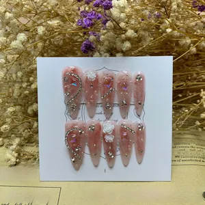 Detail of pink almond press-on nails with 3D white camellia and rhinestone accents