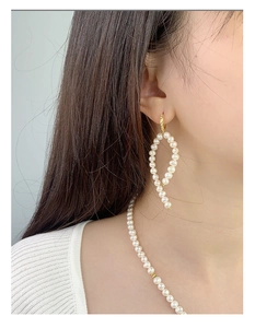 Detail of baroque pearl earring set showing the golden circular drop design on model
