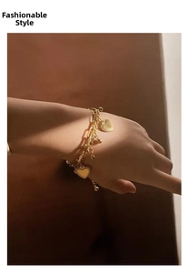Detail showing a layered golden heart bracelet with mixed chains on a model's wrist