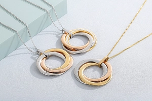 Detail of interlocking tricolor metal rings with crystal pavé on a fine chain