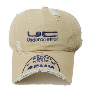 Close-up of distressed khaki canvas baseball cap with blue embroidery and ripped details