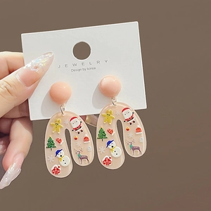 Detail showing hand-held Christmas U-shaped earrings with colorful holiday patterns