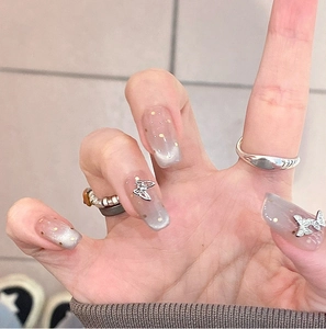 Detail of cat-eye press-on nails with silver 3D metal butterfly and glitter accents