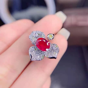 Detailed close-up of a flower ring featuring oval red gem and micro-pave crystals