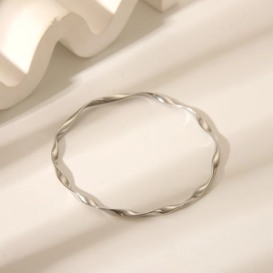 Classic silver Mobius twist bangle in stainless steel on white geometric background