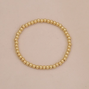 Top view of shiny gold beaded bracelet with polished round beads on beige background