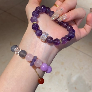 Close-up of beaded agate and amethyst bracelets with gold spacers on a model's wrist