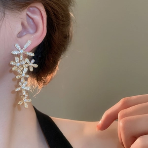 Close-up of golden floral tassel earrings with zircon inlay worn by a female model