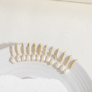 Macro shot of gold zircon earrings with fresh water pearls on a ceramic dish edge