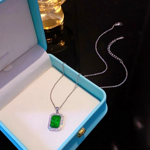 Macro shot of rectangular emerald pendant with pave crystal border on a silver chain