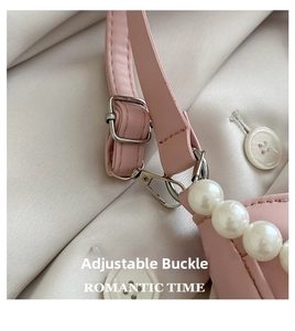 Close-up of pink pearl handbag featuring adjustable silver buckle and textured material