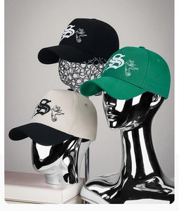 Detailed close-up showing embroidered S letter and bird motif on various cotton baseball caps
