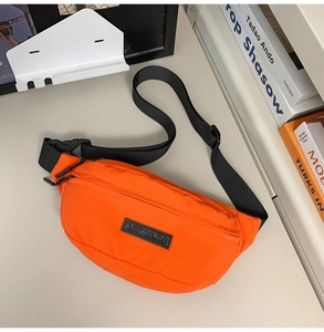 Detail of bright orange nylon crossbody bag with black logo and adjustable strap
