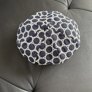 Navy blue beret with white lace crochet dots shown in a top-down flat lay view