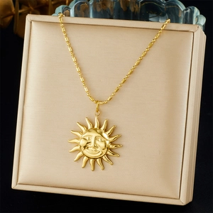Detalle de collar con colgante de sol dorado y cadena de bolas en una caja de regalo