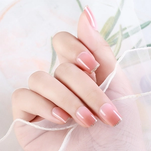Pink gradient press-on nails with gold glitter tips and glossy finish on model's hand