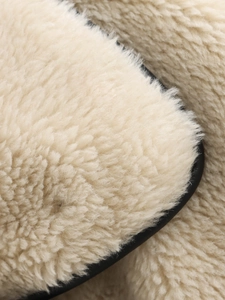 Close-up of thick cream faux fur texture with black leather trim on a fashion coat