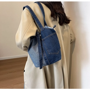 Detail of color-block denim bucket bag featuring external pocket and shoulder strap