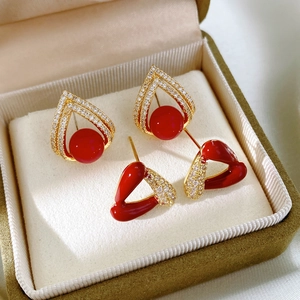 Détail de boucles d'oreilles en émail rouge et zircons dans un coffret à bijoux vert olive