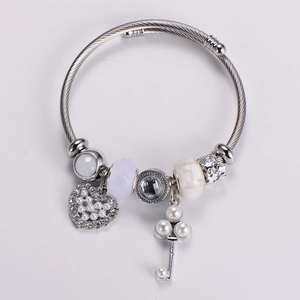 Detail of silver beaded bracelet featuring heart charm, key pendant and shell pearl accents