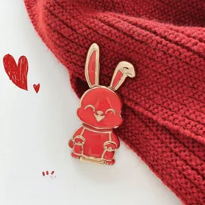 Primer plano del pin de esmalte de conejo rojo en una prenda de punto roja de invierno