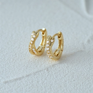 Detail of S925 sterling silver gold twisted hoop earrings with sparkling zircon stones