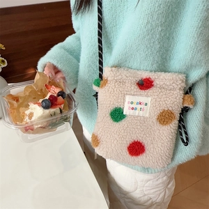 Close-up of fluffy cream plush crossbody bag featuring colorful polka dots and cord strap