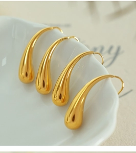 Macro shot of two pairs of gold teardrop earrings on a white ceramic dish