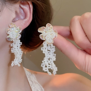 Close-up of floral tassel earrings with iridescent petals and white beaded fringes