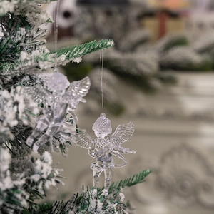 Macro view of transparent acrylic angel ornament hanging on a snowy Christmas tree