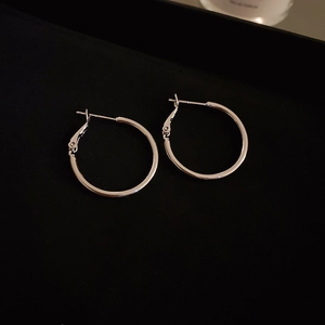 Close-up of minimalist silver hoop earrings with irregular circular design and metallic finish