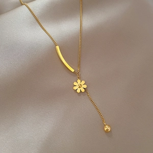 Detailed close-up of a golden flower pendant necklace with beads on silk fabric