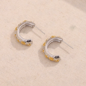 Two-tone C-shaped hoop earrings with gold floral accents on hammered silver finish