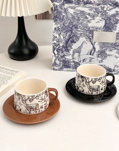 Detail of vintage ceramic coffee cups with deer motifs and matching saucers on a table