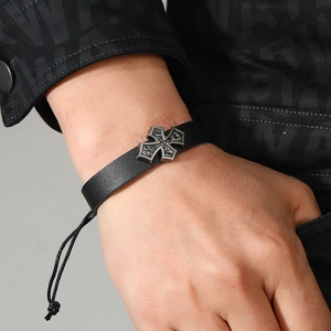Detail of adjustable black woven leather bracelet with vintage silver cross on male wrist