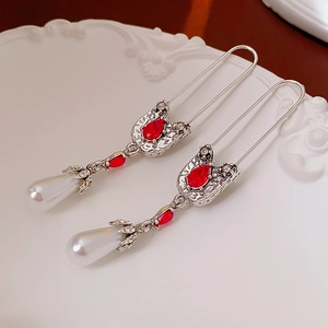 Vintage safety pin earrings with red teardrop gems and white pearls on an elegant white tray