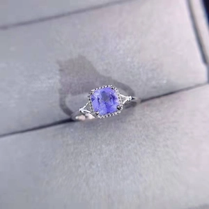 Macro detail of square purple gemstone ring with halo diamonds in grey velvet box
