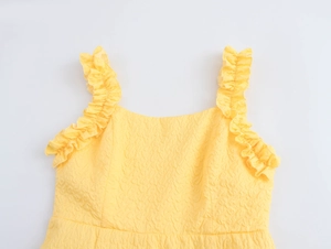 Detail of yellow textured jacquard dress showing ruffle shoulder straps and fabric finish