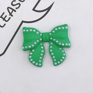 Detail of green resin bow charm with white pearl embellishments for DIY phone cases