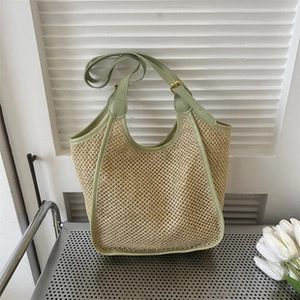 Close-up of straw tote bag with green leather trim on a metal rack with tulips