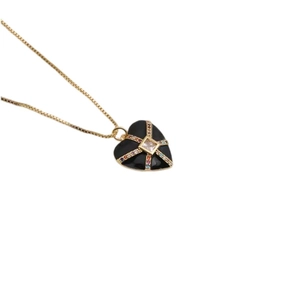 Vue détaillée du pendentif cœur noir avec lignes dorées et zircons colorés