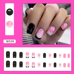 Detail view of pink gradient and black French tip press-on nails with glitter hearts